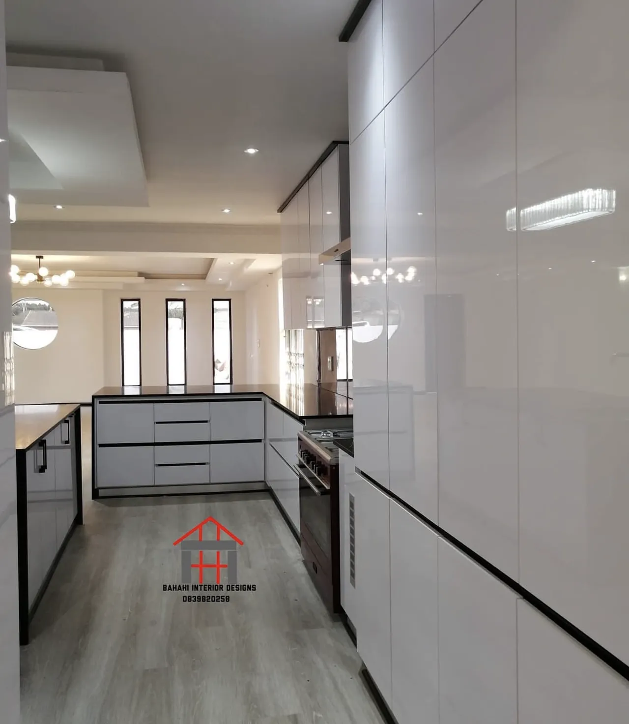 A run of iceberg white gloss tall units with a black trim line, looking through to the kitchen and dining room.
