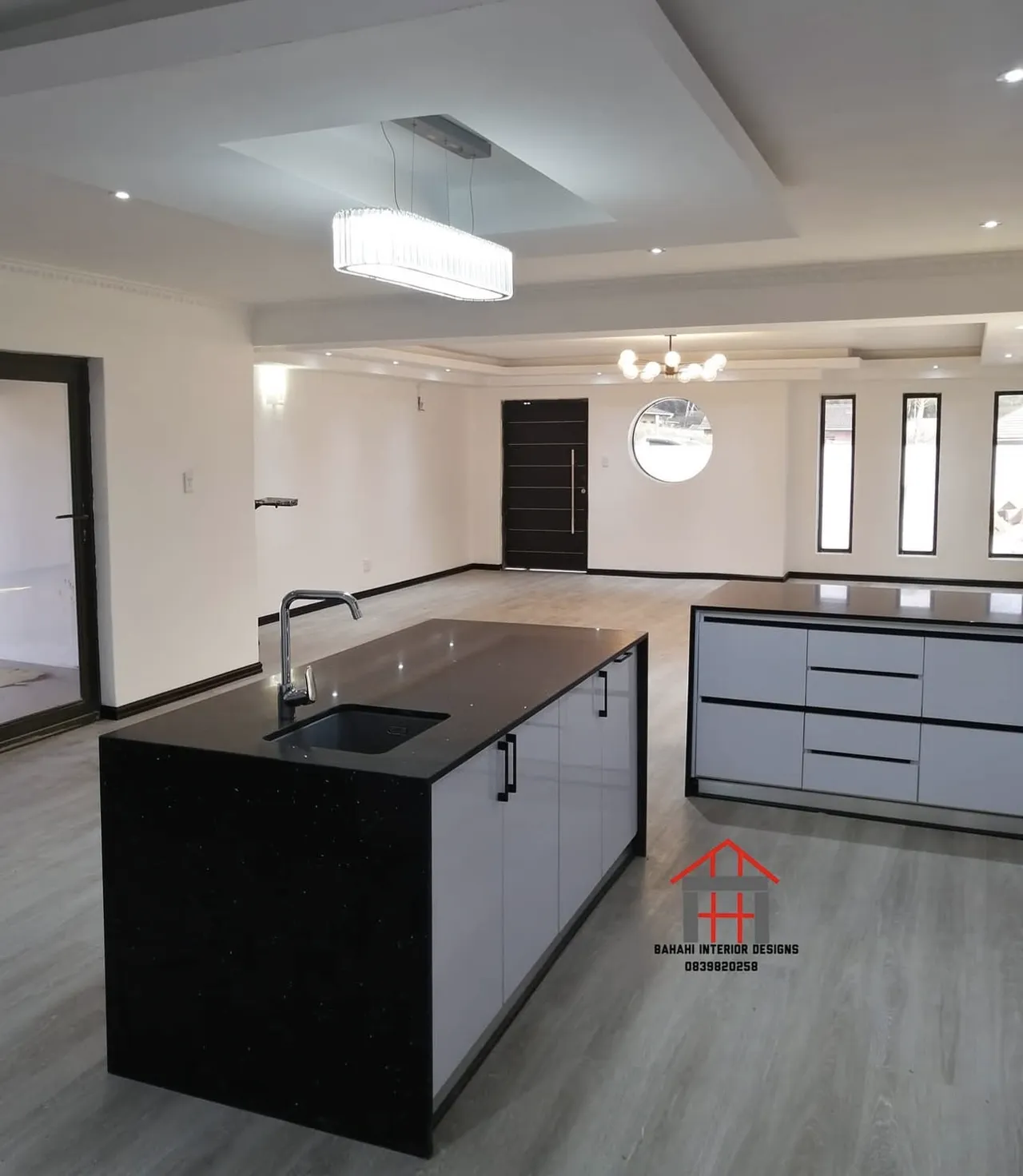 A black waterfall island with an undermount sink and white gloss doors, in an open-plan living space.