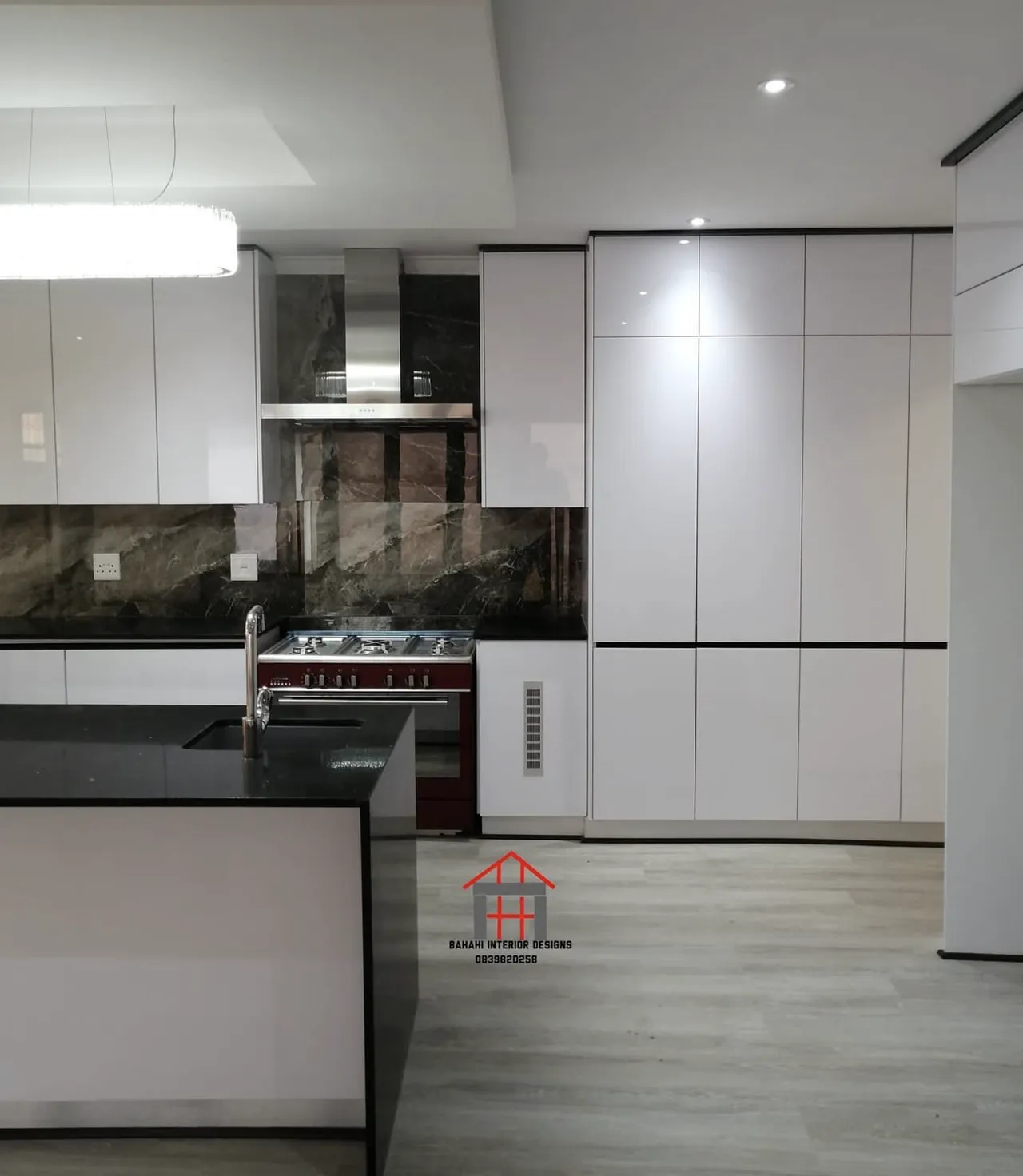 A floor-to-ceiling wall of white gloss handleless units beside the cooker and extractor hood.
