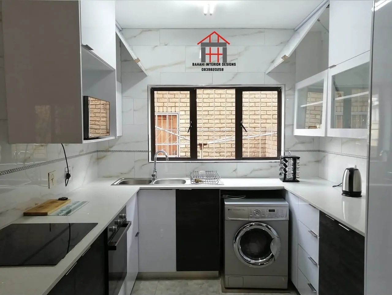 A white gloss U-shaped kitchen with dark oak-grain base doors, white quartz tops and glass-fronted wall units.