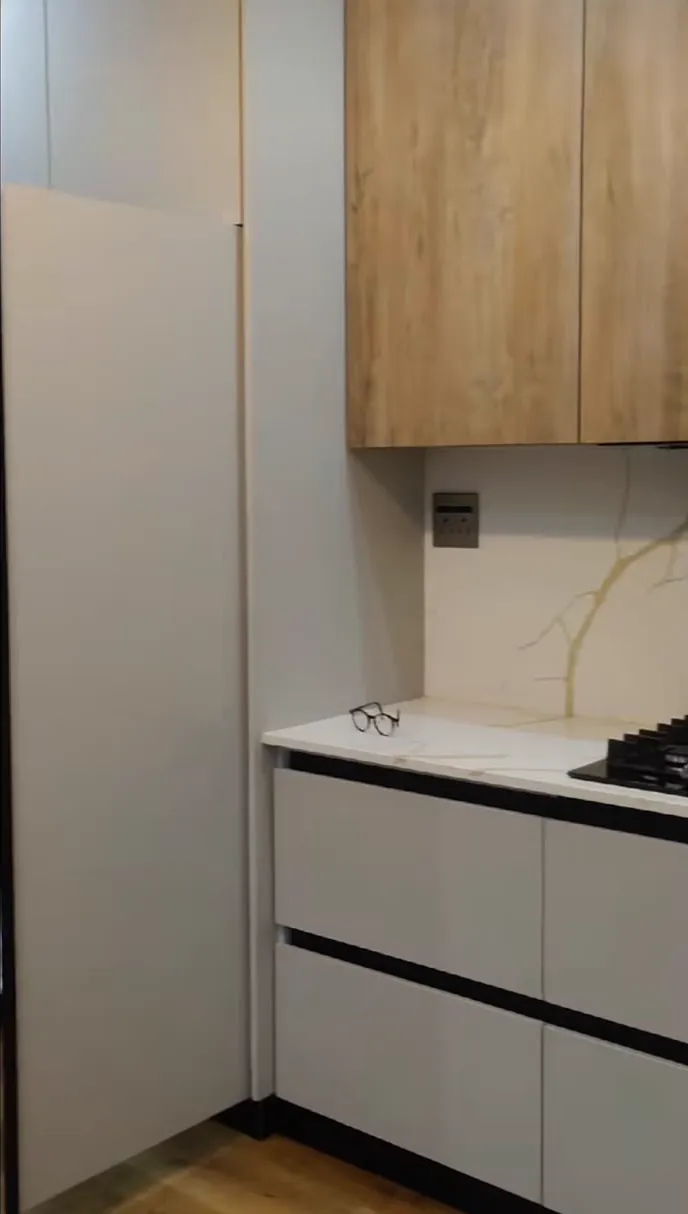 Oak-grain wall cupboards over light grey handleless drawers with black channel pulls.