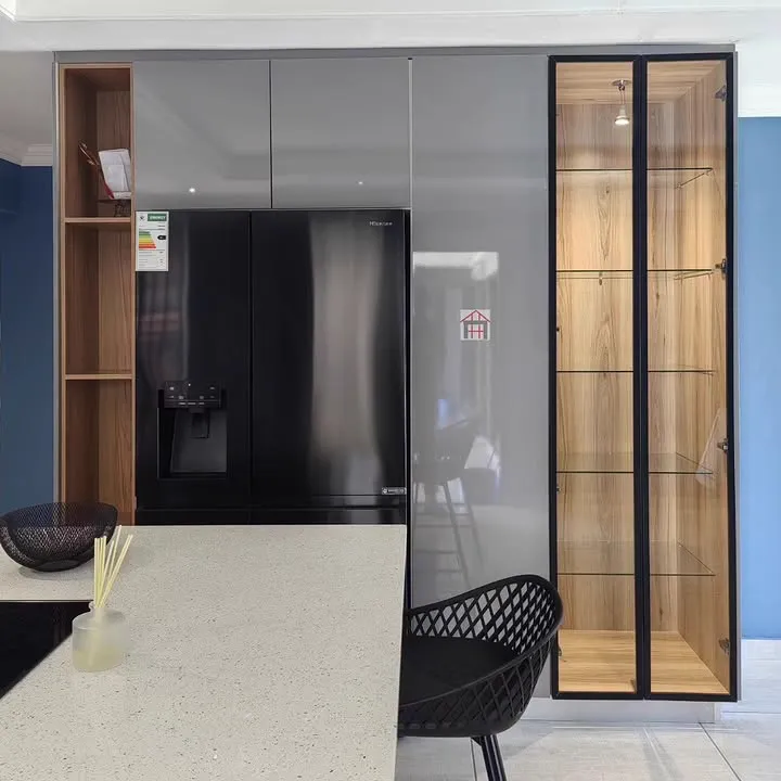 A black fridge set into grey gloss tall units beside a lit black-framed glass cabinet.