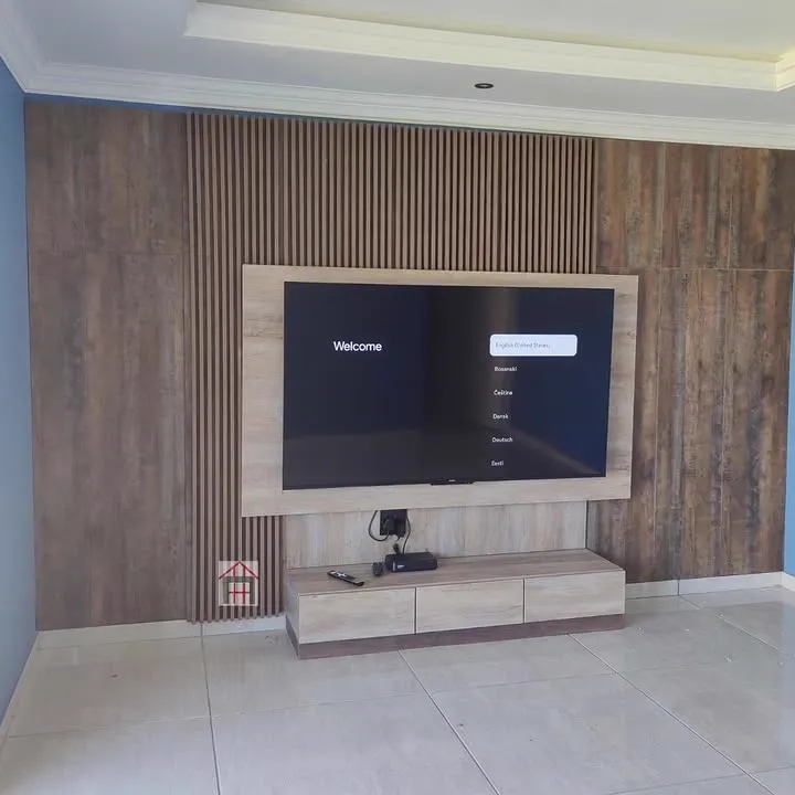 A full TV wall in dark timber panelling with a strip of slats and a floating console.