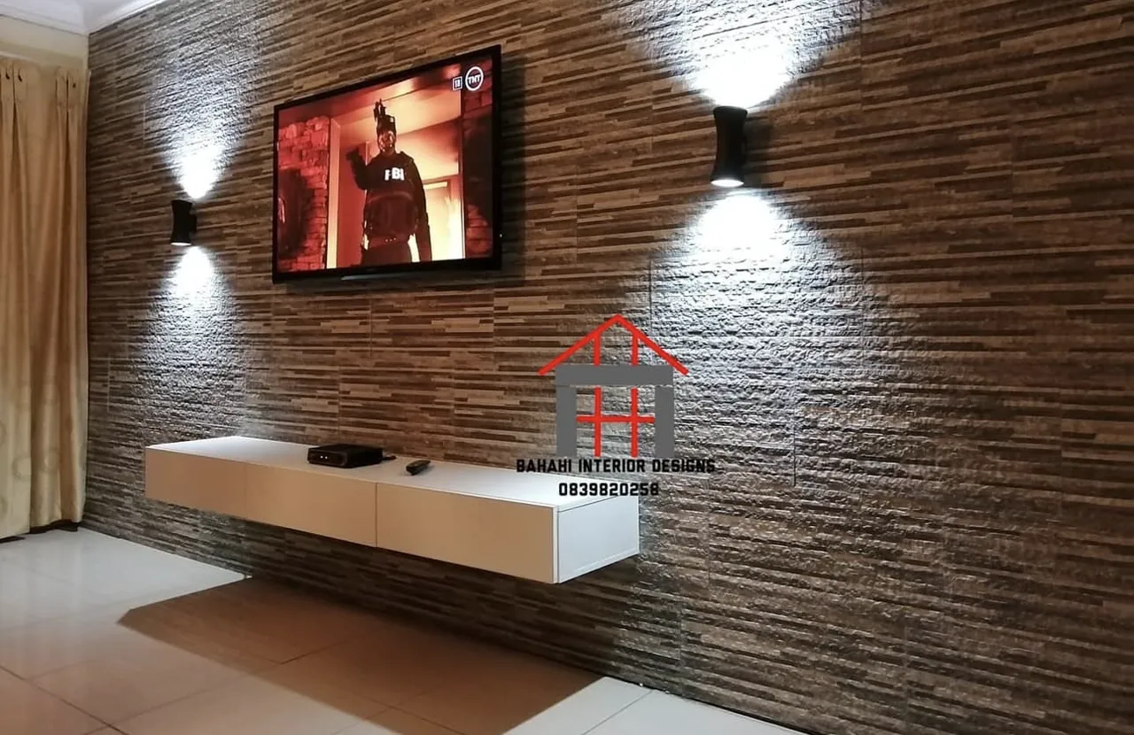 The tile-clad TV wall from the side, lit by two up-and-down wall lights.