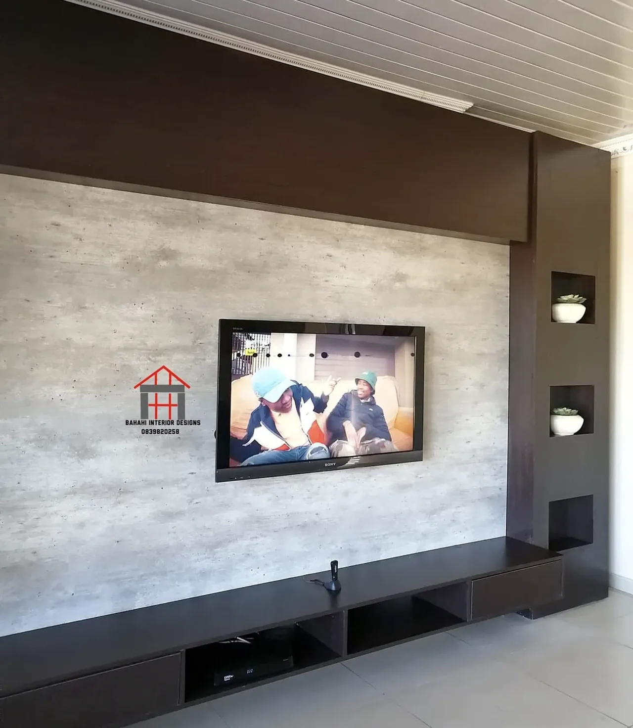 A wall-mounted TV stand in African wenge with a natural stone panel and a column of display niches.