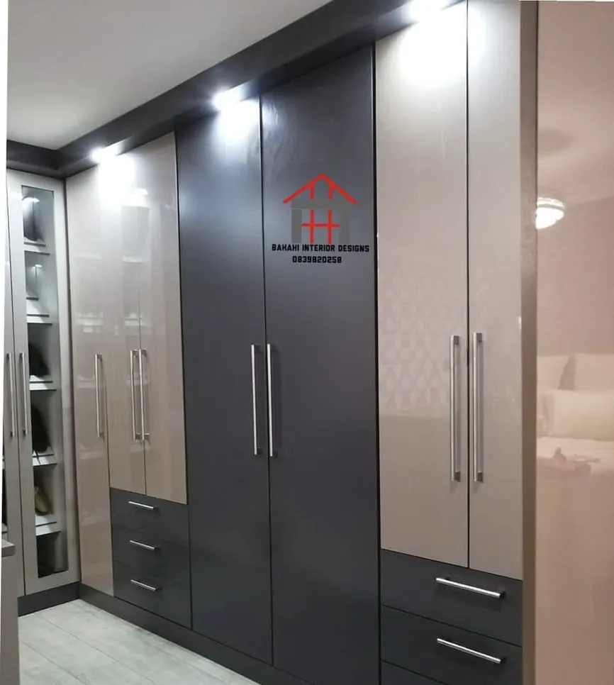 Cappuccino and storm grey gloss wardrobe doors with drawers below, lit from the bulkhead above.