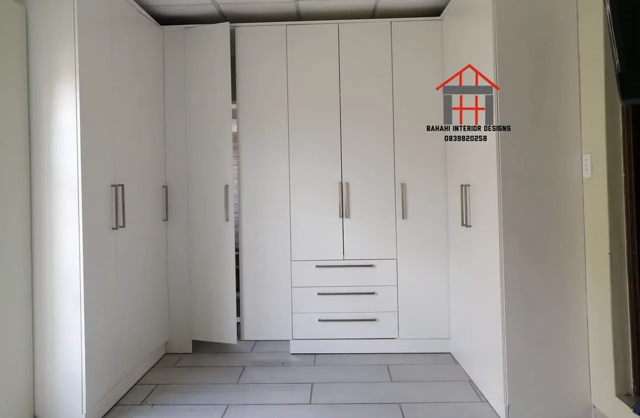 A white three-wall bedroom cupboard with a shoe-rack section, drawers, shelving and hanging space.